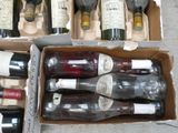 several bottles of wine are in a cardboard box on the ground