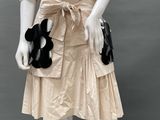 an image of a mannequin dressed in a beige dress with a black flower on it