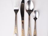 four silver spoons and two silver spoons on a white table