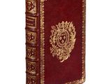 an old red book with gold trim sitting on top of a white surface