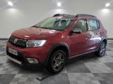 une photo d'une Dacia rouge garée sur un sol à damier