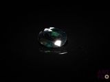 un gros plan d'un diamant vert à facettes posé sur une surface noire