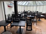 tables and chairs in a restaurant with a skylight in the background