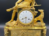 une image représentant une horloge en or surmontée d'une statue de femme