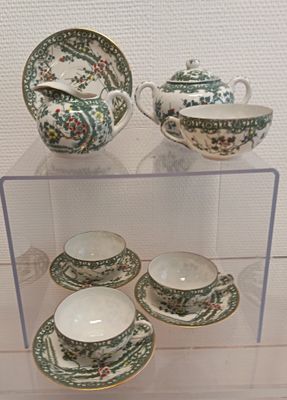 une vitrine sur laquelle sont disposées des tasses à thé et leurs soucoupes