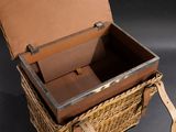 a wicker basket with a leather handle on a black background