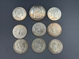 six different types of silver coins on a black surface