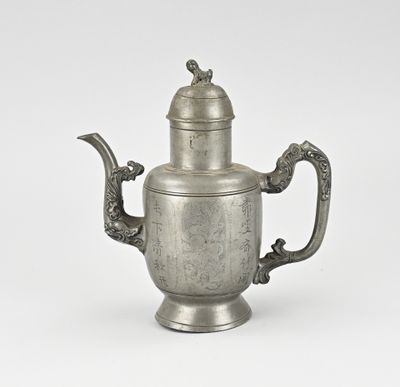 une vieille théière en argent avec une anse et un couvercle