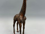 statue d'une girafe debout sur une surface blanche, avec un fond gris