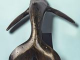bronze whale head on a black stand against a blue background