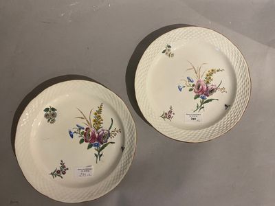 two plates with floral designs on them sitting on a table