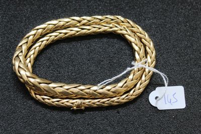 gros plan d'un bracelet en or sur une surface noire
