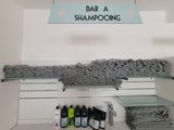 une étagère sur laquelle sont posés des serviettes et des shampoings, dans une salle de bains