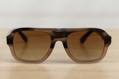sunglasses on a wooden table with a white wall in the background