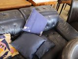 a black leather couch with pillows on it in a living room