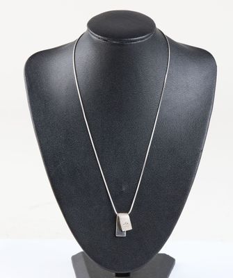 silver necklace with a rectangle shaped pendant on a black mannequin