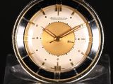 an image of a gold and black clock sitting on top of a clear base