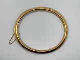 gros plan d'un bracelet en or sur une surface blanche