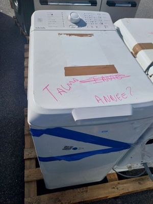 une machine à laver posée sur une palette, à côté d'une poubelle