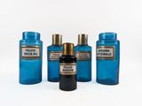 four blue glass bottles are lined up on a white surface
