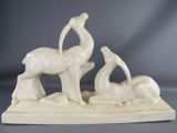 a white sculpture of a bird and a bird on a rock