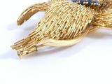yellow gold tone flower brooch with blue stones on it