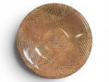 une assiette marron posée sur une surface blanche, sur fond blanc