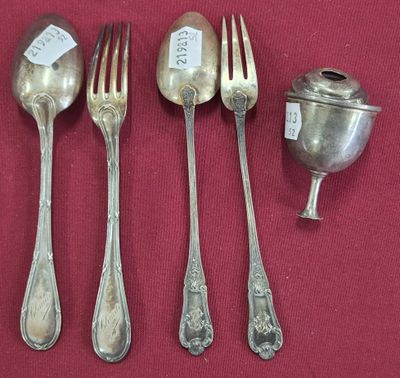 quatre cuillères en argent et une cuillère à café en argent posées sur un napperon rouge