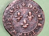an old coin with a fleur on it sitting on a green surface
