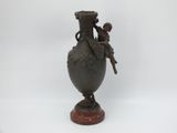 un vase en bronze sur lequel sont assis un garçon et une fille