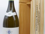 une bouteille de vin blanc dans un coffret en bois, à côté d'une bouteille de vin