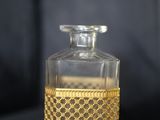 une bouteille en verre avec un bouchon doré posée sur une surface noire