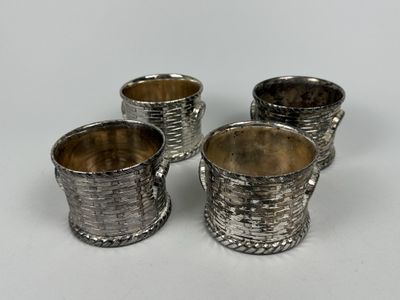 four silver plated cups sitting on top of a white surface