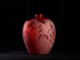a red vase sitting on a table with a black background