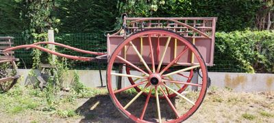 un chariot rouge posé dans l'herbe