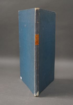 un vieux livre bleu posé sur une table près d'un mur gris