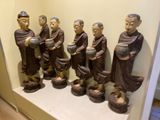 many statues of monks on a shelf in a room