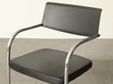 a black leather chair with a chrome frame on a concrete floor