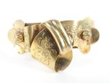 a close up of a gold bracelet with a flower design on it