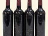four bottles of wine are lined up in a row on a white surface