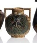 trois vases munis d'anses de chaque côté, posés sur une surface blanche