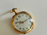 a gold pocket watch sitting on a white surface