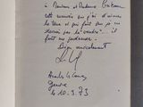 un livre ouvert, sur lequel est inscrit un poème manuscrit, posé sur une table