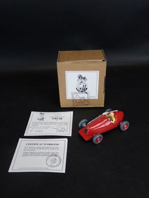 une petite voiture rouge posée sur une table à côté d'une boîte