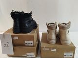 pair of black and gold boots sitting on boxes on a white surface