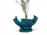 a blue vase with a plant in it on a stand