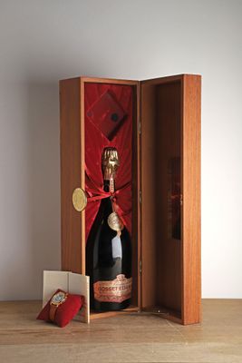 une bouteille de champagne dans un coffret en bois orné d'un ruban rouge
