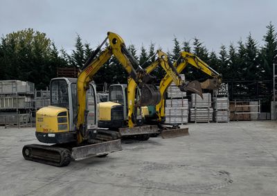 three excavators that are parked in a parking lot