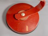 a red object with a metal handle on a white surface