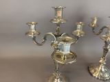 three silver candelabs with a clock on each of them